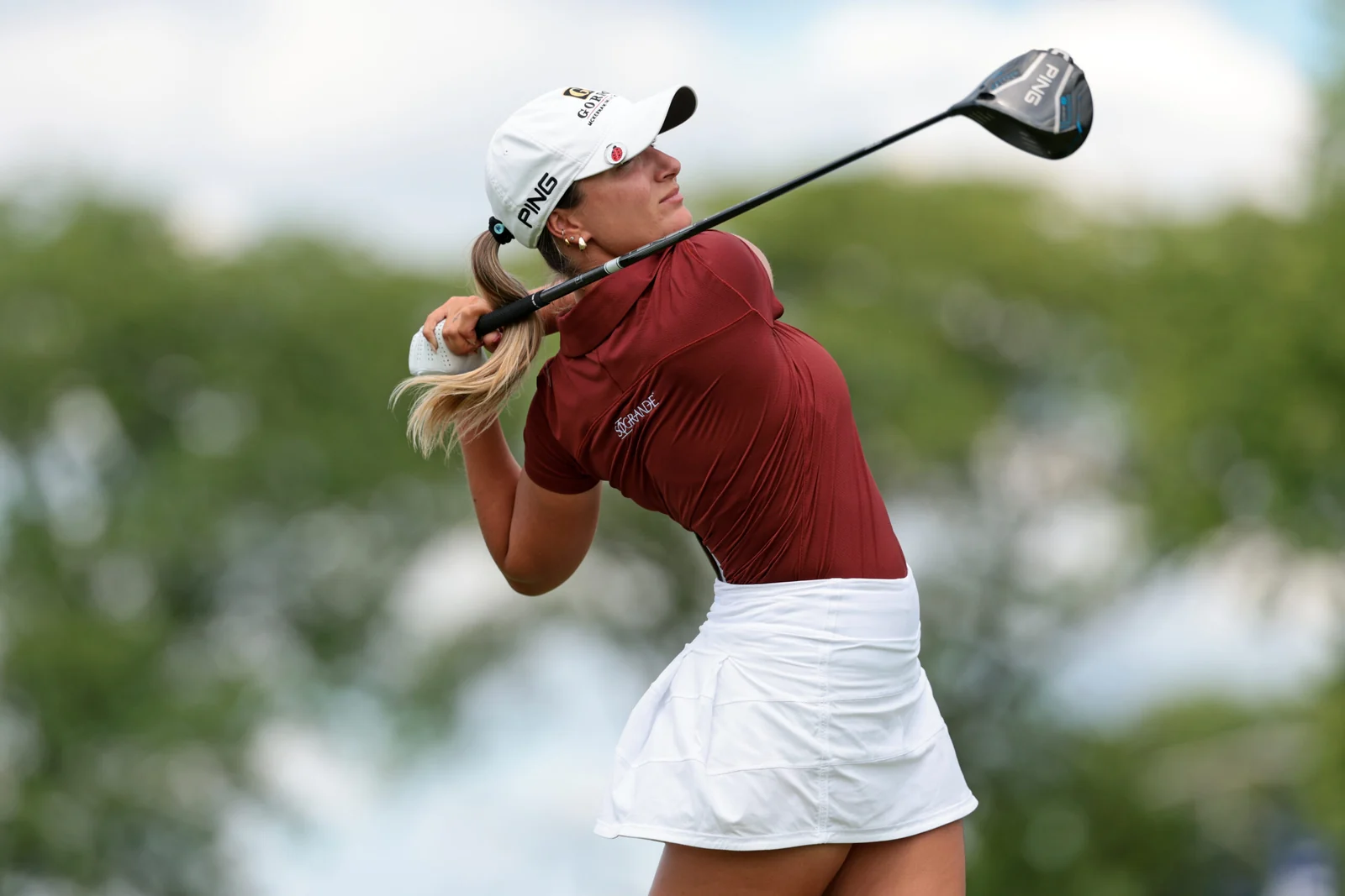 Carla Tejedo termina un swing con polo rojo, logo de Sotogrande en la manga y gorra blanca de Gordon.